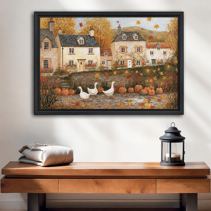 Black-framed folk art autumn village wall art above a wooden console beside folded linens and a candle lantern