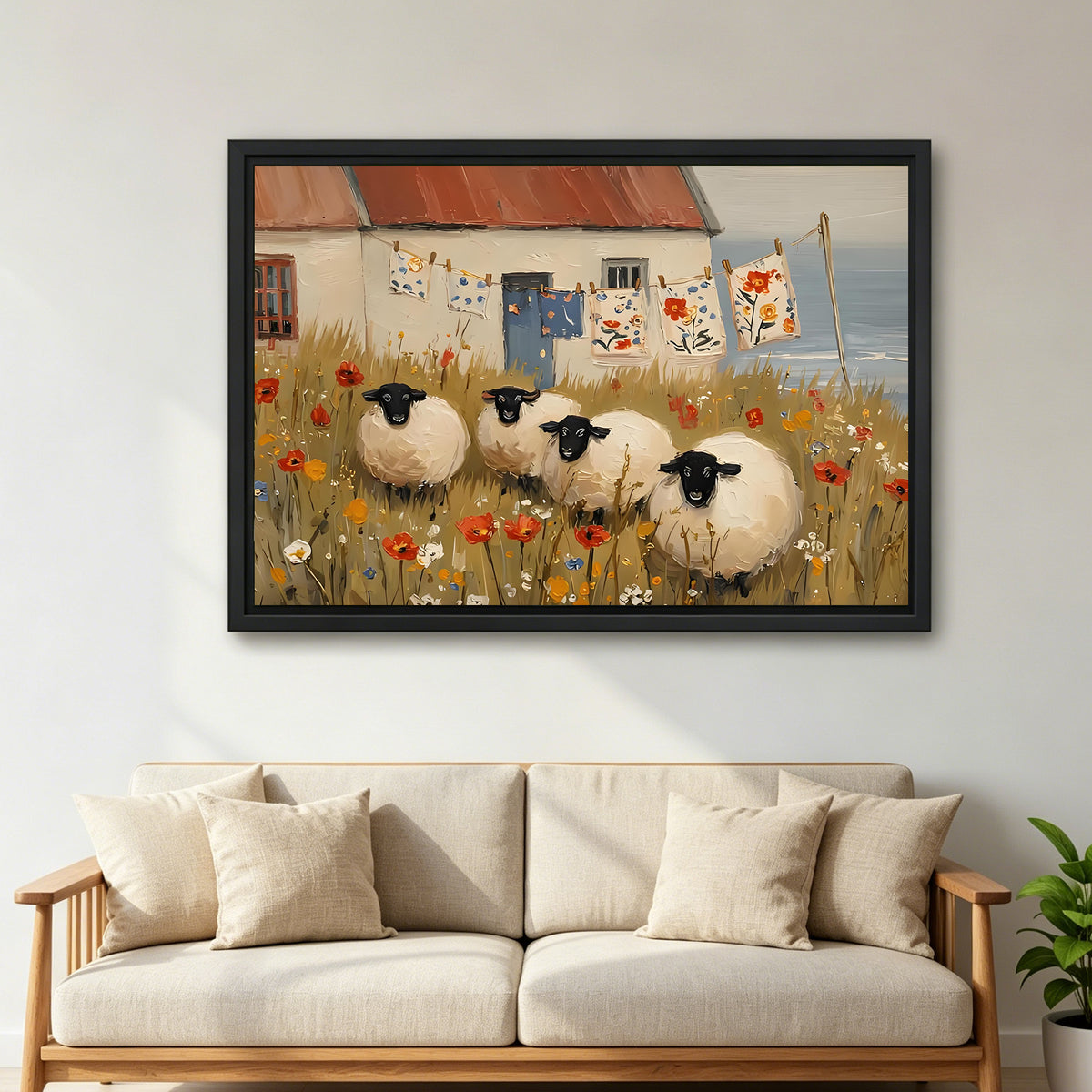 Folk art four black-faced sheep red poppy wildflower meadow coastal cottage black framed canvas wall art on light gray wall above wide cream linen wood-arm sofa with throw pillows and green plant