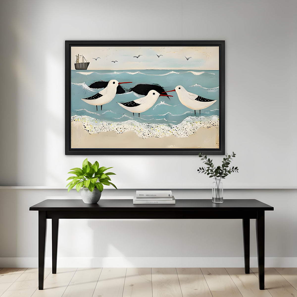 Three shorebirds folk art beach canvas framed print on white wall above black console with green plant