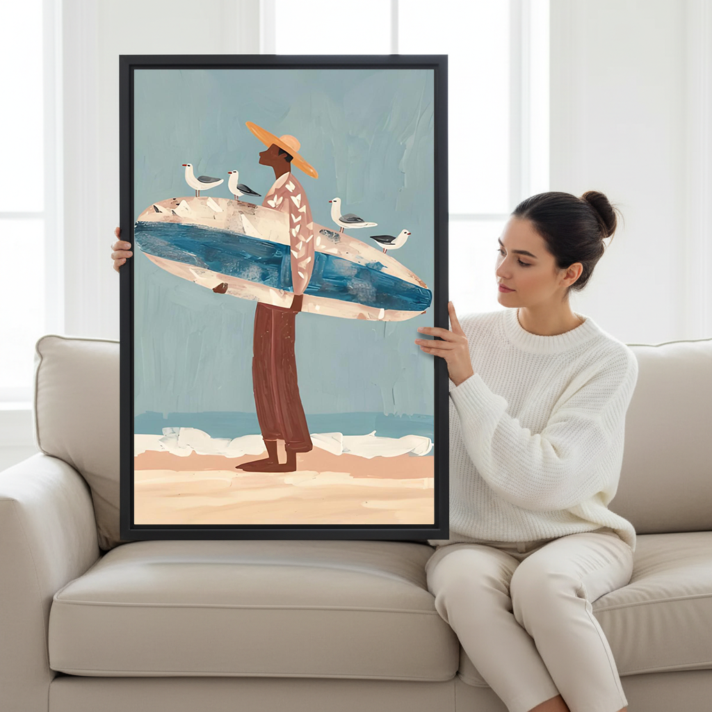 Woman holding folk art surfer with seagulls framed canvas wall art on cream sofa, showing large print size with coastal beach illustration in warm sandy tones