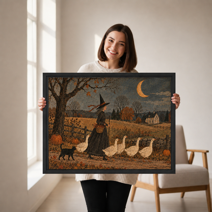 Woman holding framed folk art witch and geese wall art featuring a black cat, pumpkins, and golden crescent moon.