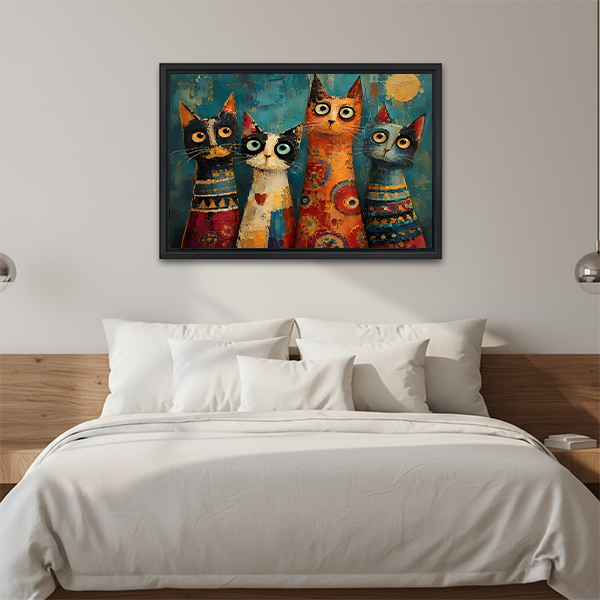 Whimsical four cats canvas wall art in a black frame above a cream sofa.