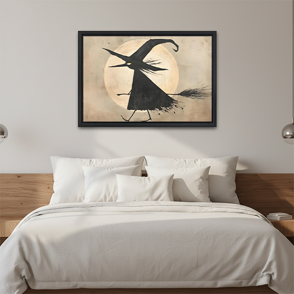 Framed flying witch moon canvas wall art displayed above a bed in a calm neutral bedroom