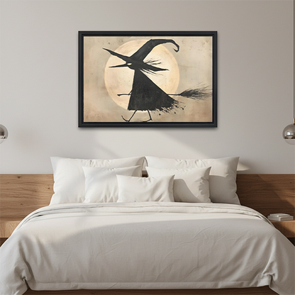 Framed flying witch moon canvas wall art displayed above a bed in a calm neutral bedroom