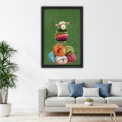 Framed knitting sheep canvas wall art displayed above a white sofa with blue accent pillows.