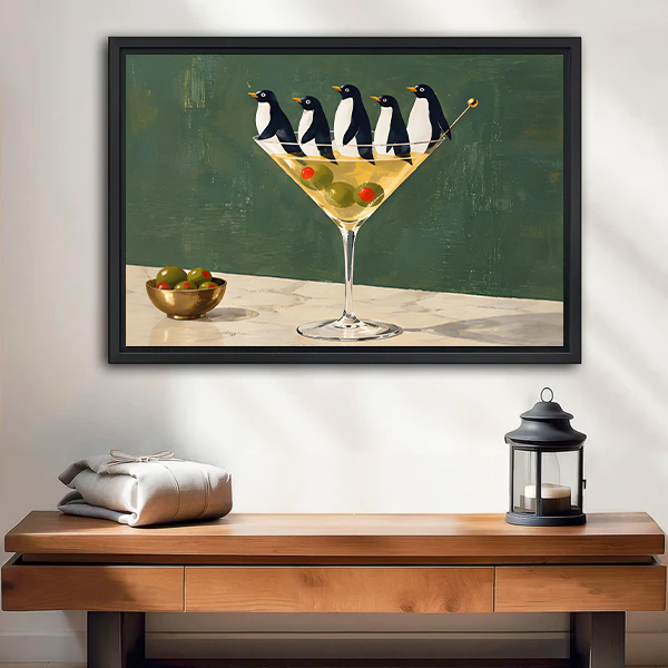 Framed penguin martini canvas wall art displayed above a cream sofa in a bright living room.