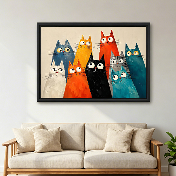 Framed quirky cats canvas wall art displayed above a cream sofa with cushions in a living room.