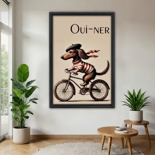 French dachshund Oui-ner bicycle vintage poster wall art in black frame, displayed in minimalist entryway with large fiddle leaf fig and small aloe plant