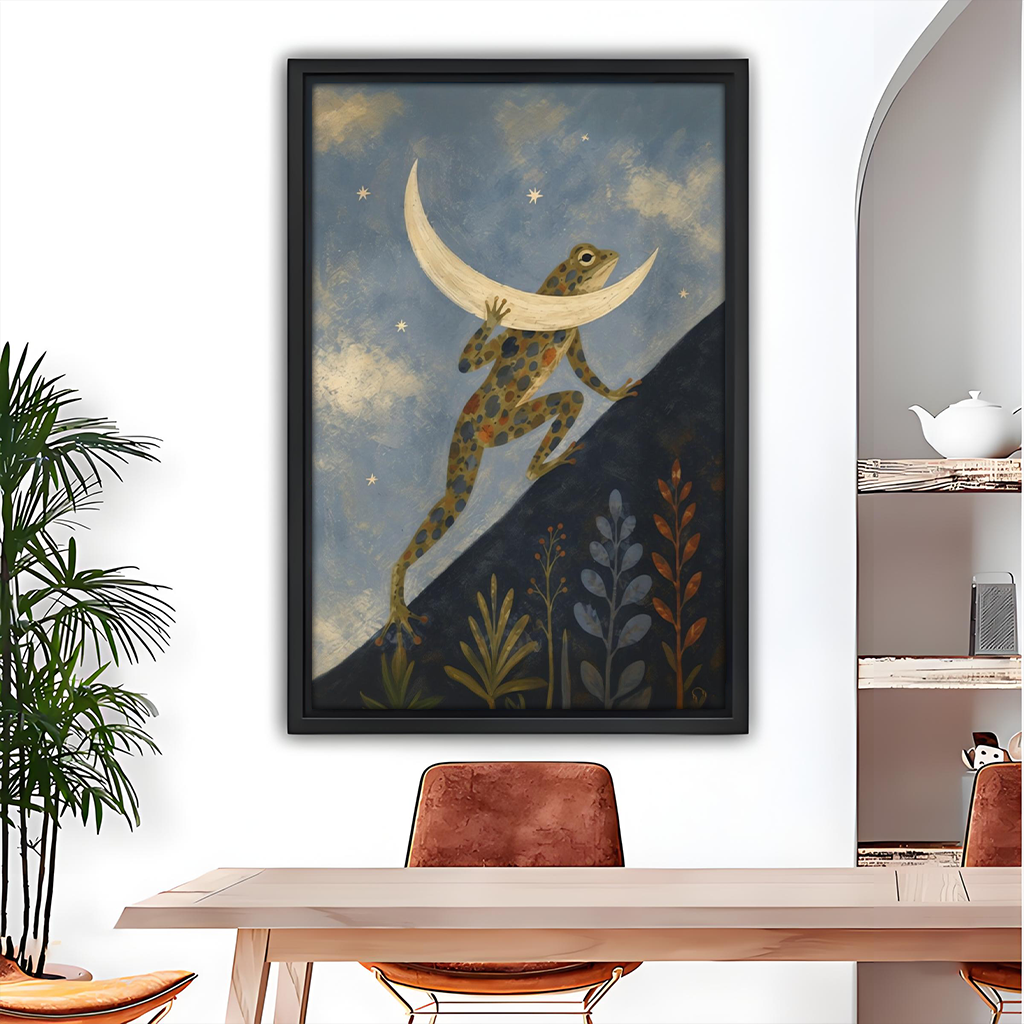 Black framed folk art frog carrying the moon canvas wall art above a wooden dining table with rust chairs