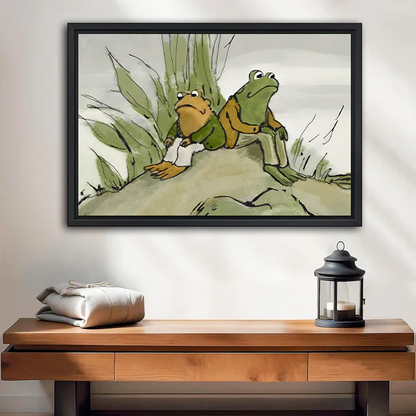 Black-framed frog friends canvas wall art showing two seated companions beneath a tree above a wooden console.
