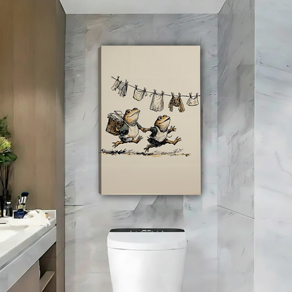 Two women smiling beside framed frog laundry canvas wall art featuring a vintage illustration of frogs and hanging clothes.