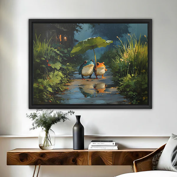 Framed frogs leaf umbrella canvas wall art hangs above a wooden console with flowers and books.