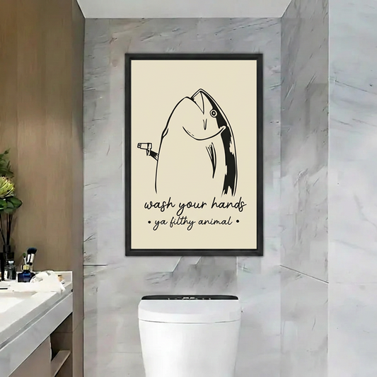 Funny fish wall art featuring a handwashing quote in a black frame above a toilet in a marble bathroom.