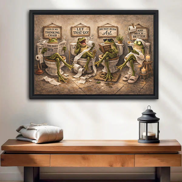 Whimsical frogs bathroom canvas wall art in a black frame above a wooden console with a lantern.