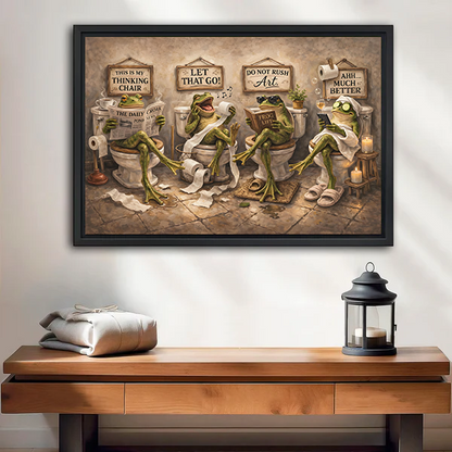 Whimsical frogs bathroom canvas wall art in a black frame above a wooden console with a lantern.