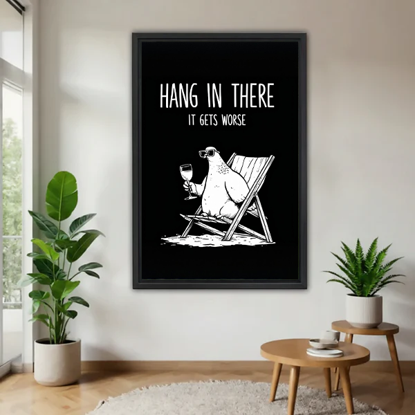 Black-framed funny polar bear canvas wall art between potted plants, showing a lounging bear beneath sarcastic white lettering.