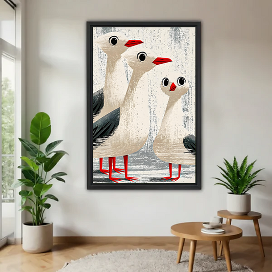 Funny seagull trio vintage coastal framed canvas wall art with black frame displayed in bright living room with plants