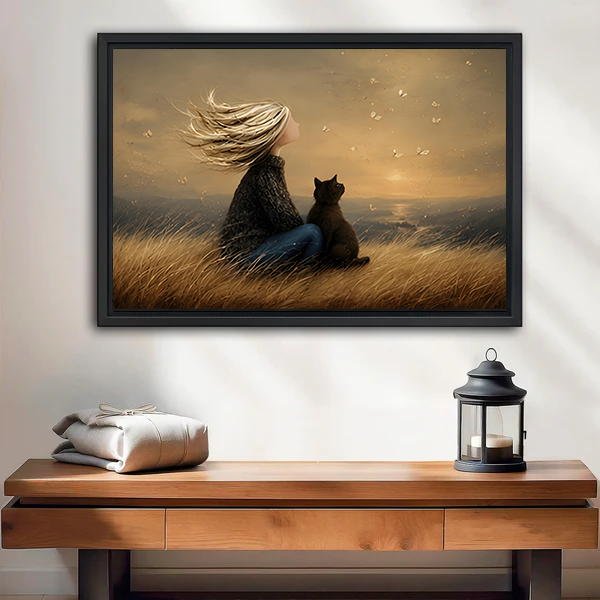 Framed canvas wall art of a girl and black cat sitting in golden grass, warm vintage tone, displayed above a wooden console table