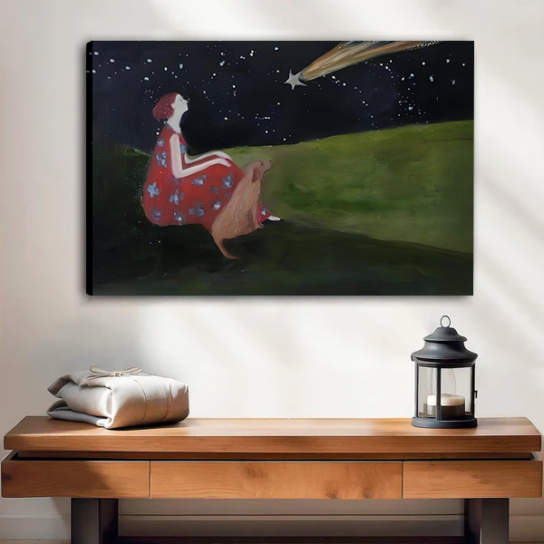 Canvas art print of a girl in a red dress and deer sitting on a green hillside gazing at a shooting star in a starry night sky, displayed above a wooden console table