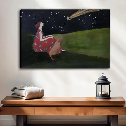 Canvas art print of a girl in a red dress and deer sitting on a green hillside gazing at a shooting star in a starry night sky, displayed above a wooden console table