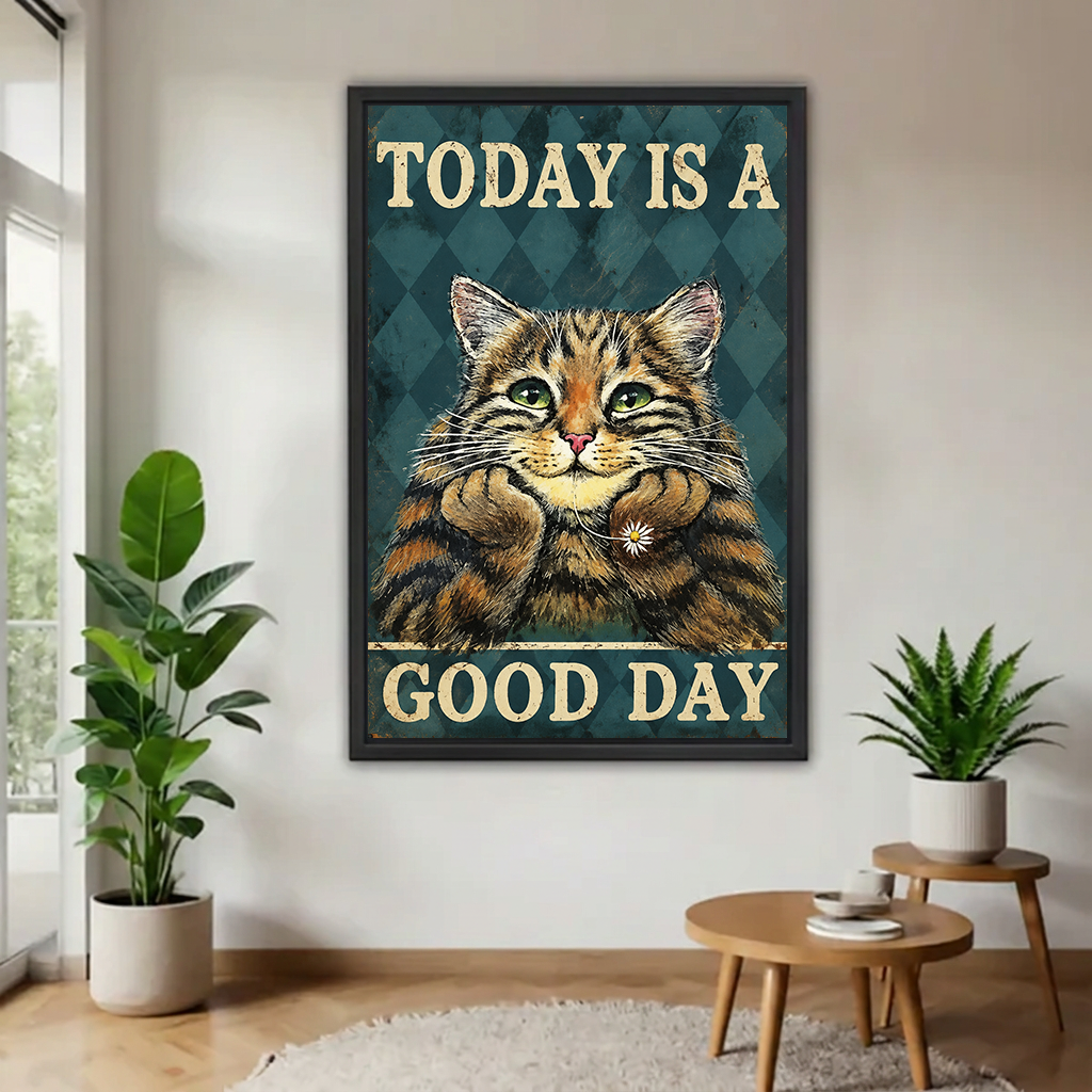 Good Day cat canvas wall art in a black frame displayed between houseplants above round wooden tables.
