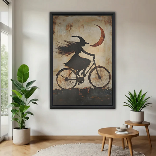 Gothic witch bicycle canvas wall art with a crescent moon displayed beside leafy plants in a bright room