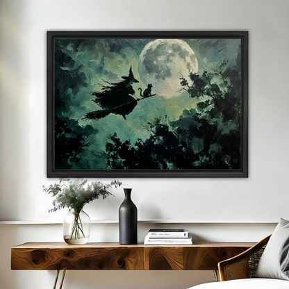 Gothic witch and black cat flying over full moon framed canvas print hung above black console table in entryway