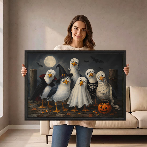 Woman holding black-framed Halloween birds canvas wall art featuring six costumed birds, bats, and an orange pumpkin bucket.