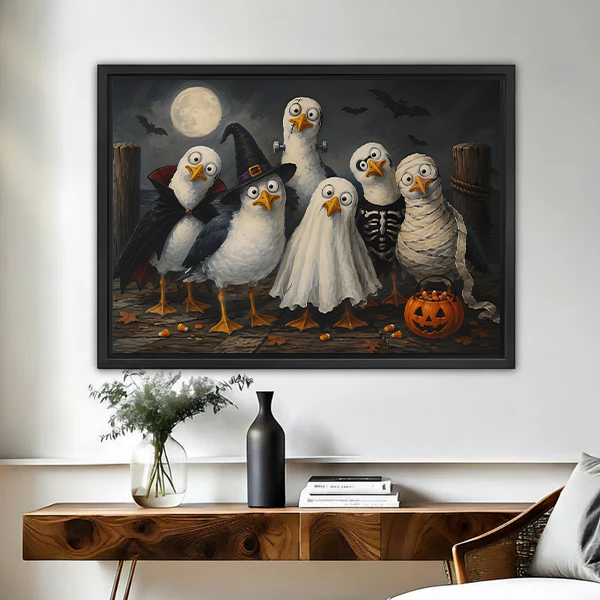 Black-framed Halloween birds canvas wall art above a wooden console, showing six costumed birds beneath a full moon.