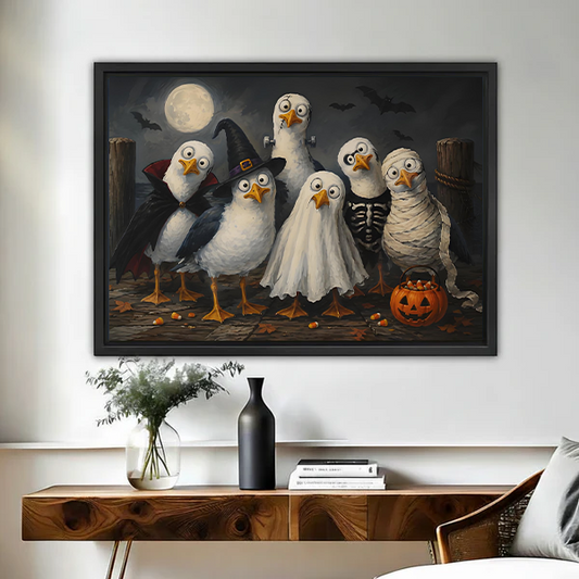 Black-framed Halloween birds canvas wall art above a wooden console, showing six costumed birds beneath a full moon.