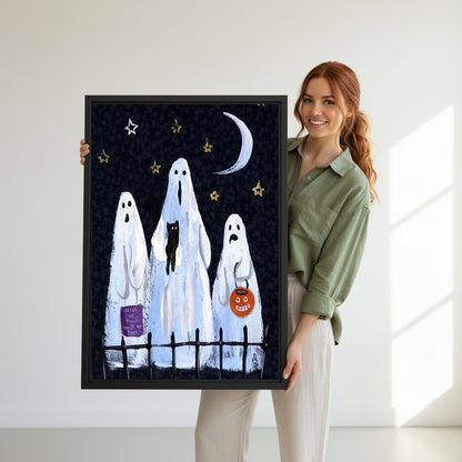 Smiling redhead woman holding large Halloween three white sheet ghosts trick or treat black cat pumpkin bucket night sky black framed canvas wall art size reference in bright white room with natural side light
