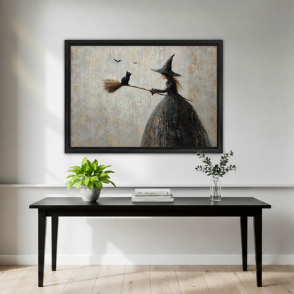 Gothic witch in tall black hat and dark dress holding broomstick with black cat on tip and two bats in pale sky framed canvas above black console table with white pot plant