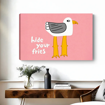 Framed Hide Your Fries seagull canvas wall art with pink background above a black bed.