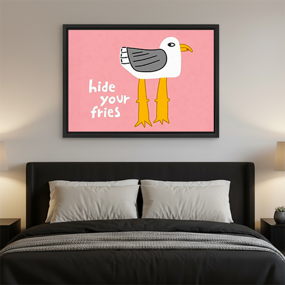 Framed Hide Your Fries seagull canvas wall art above a black console with plants and books.