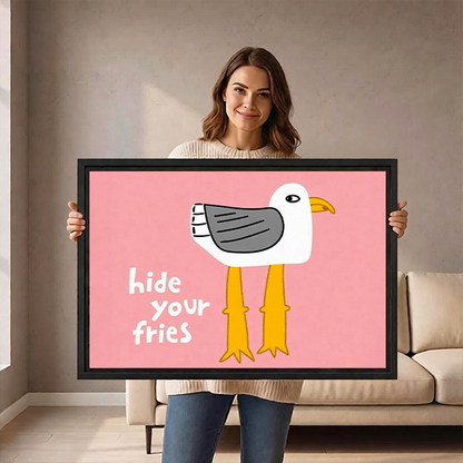 Woman holding black-framed Hide Your Fries seagull canvas wall art featuring a white bird on pink.