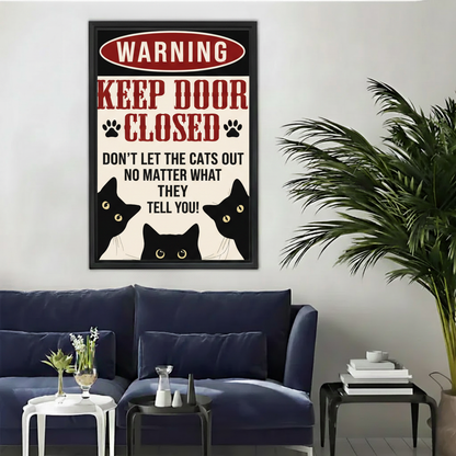 Funny warning keep door closed don't let the cats out wall art print in black frame above navy blue sofa with palm plant in modern living room