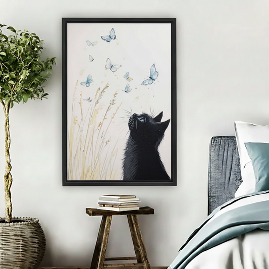 Dreamy black cat watching blue butterflies wildflower watercolor wall art print in black frame beside bed with wooden stool and wicker basket in cozy nature-inspired bedroom