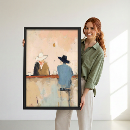 Woman holding black-framed impressionist cowboy bar canvas wall art depicting two cowboy-hatted figures across a rust-red counter.