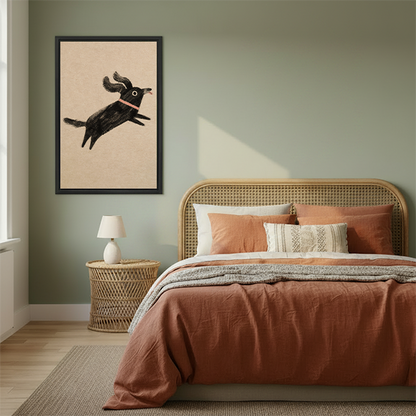 Framed whimsical jumping black dog wall art displayed in cozy bedroom with sage green walls and terracotta bedding