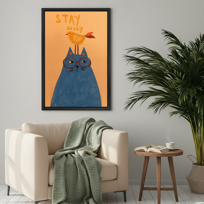 Whimsical cat and bird canvas wall art above a cream armchair with a green knitted blanket.