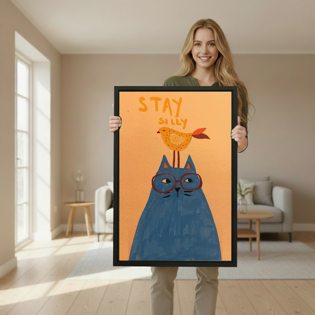 Woman holding framed whimsical cat and bird canvas wall art in a softly lit living room.