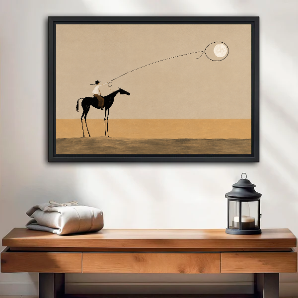 Surreal Cowboy Moon Lasso artwork in a black frame above a wooden table and lantern.