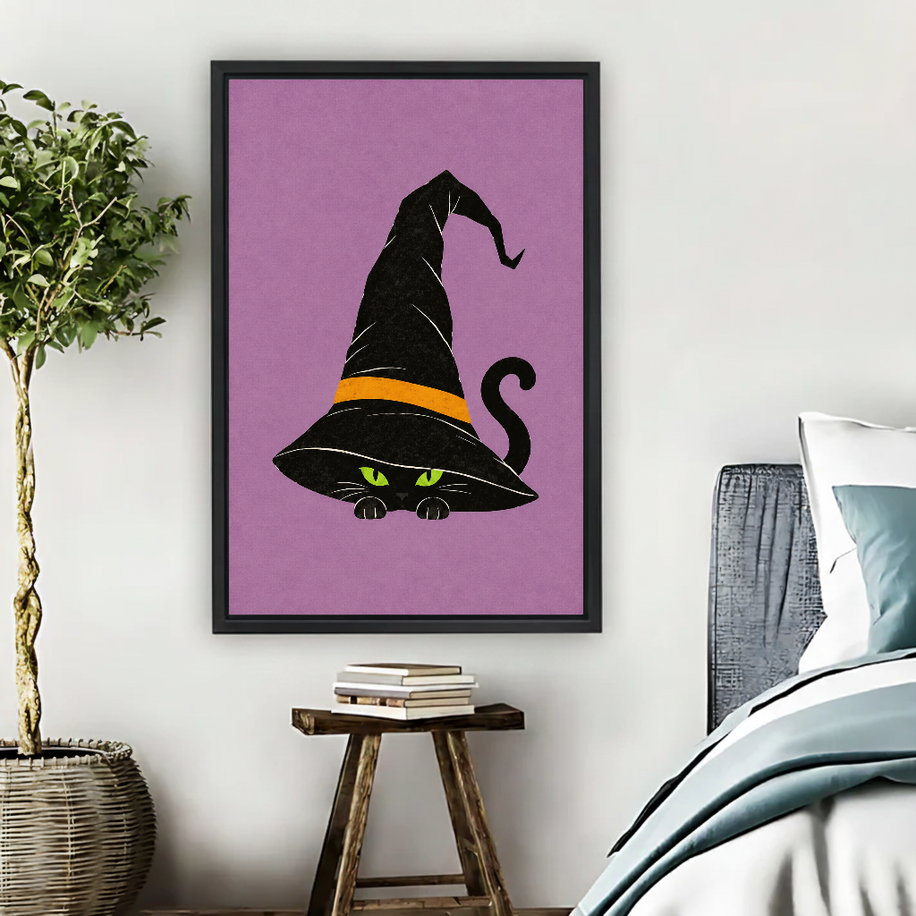 Whimsical Witch Hat Cat artwork in a black frame above a bed with blue bedding.
