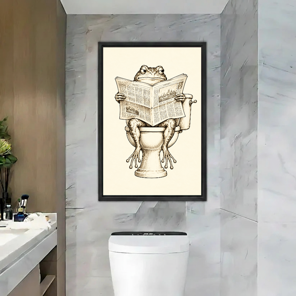 Newspaper frog canvas wall art in a black frame above a toilet against marble walls.