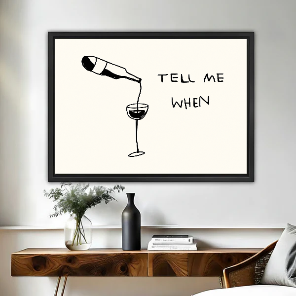 Tell Me When Wine artwork in a black frame above a live-edge wooden desk.