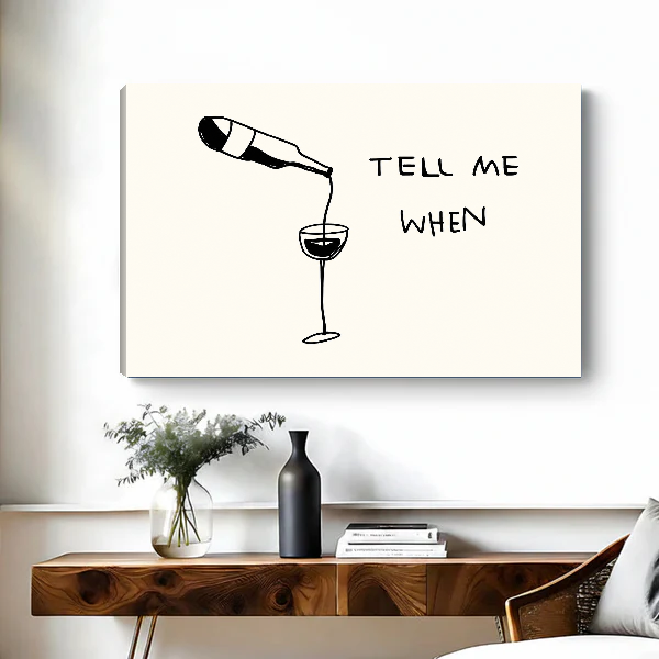 Tell Me When Wine artwork as unframed canvas above a wooden desk with black vase.