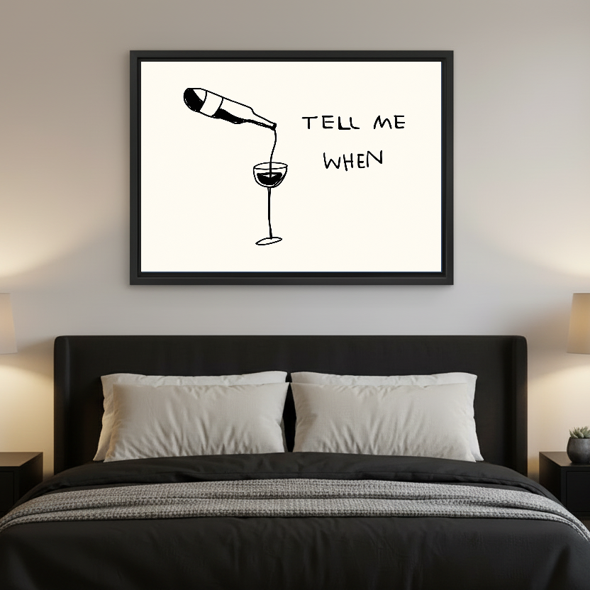 Tell Me When Wine artwork in a black frame above a bed with dark headboard.