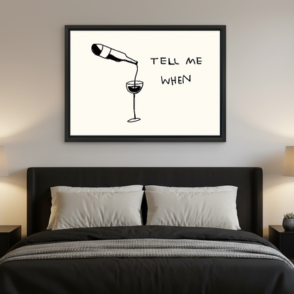 Tell Me When Wine artwork in a black frame above a bed with dark headboard.