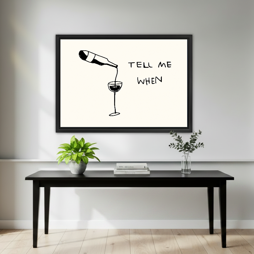 Tell Me When Wine artwork in a black frame above a black console with plants.