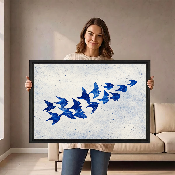 Cobalt Blue Swallows artwork held in a black frame by a woman beside a cream sofa.